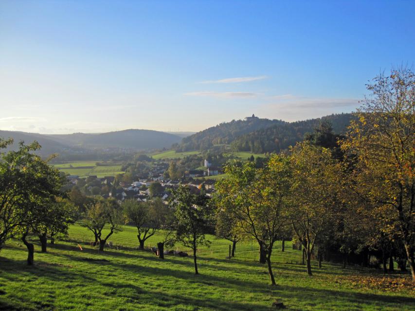 Blick in eine herbstliche Landschaft mit Streuobstwiesen, der Stadt Breuberg und der Burg Breuberg im Hintergrund
