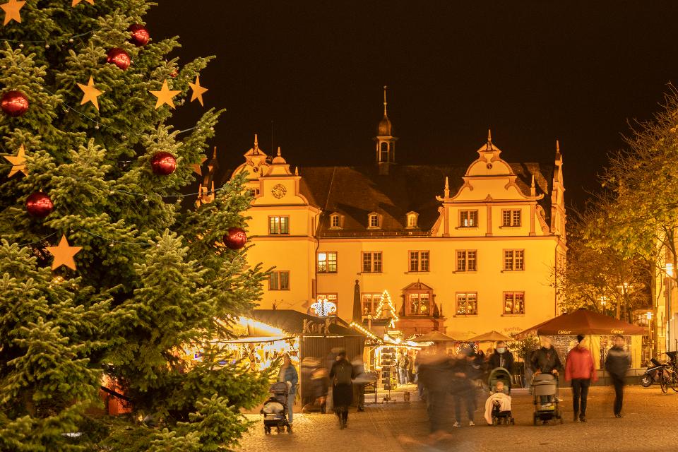 Ein geschmückter Weihnachtsbaum auf einem Marktplatz mit dem Alten Rathaus aus dem 16. Jahrhundert.