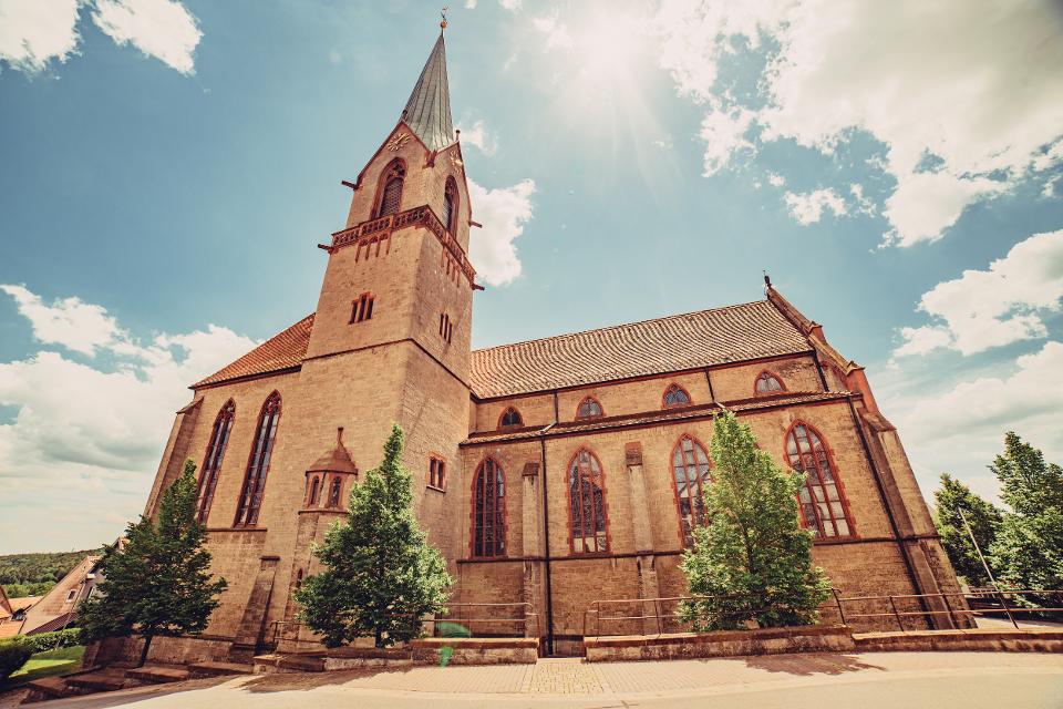 Der dominante Kirchenbau überragt das gesamte Ortsbild und ist auch den regionalen Gesteinen Muschelkalk und Bundsandstein gebaut. 