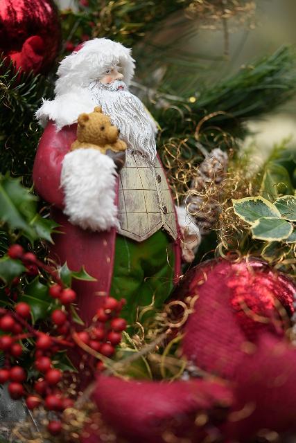 Nikolaus mit Teddy in der Hand aus Keramik vor Tannenzweigen und weihnachtliche Deko