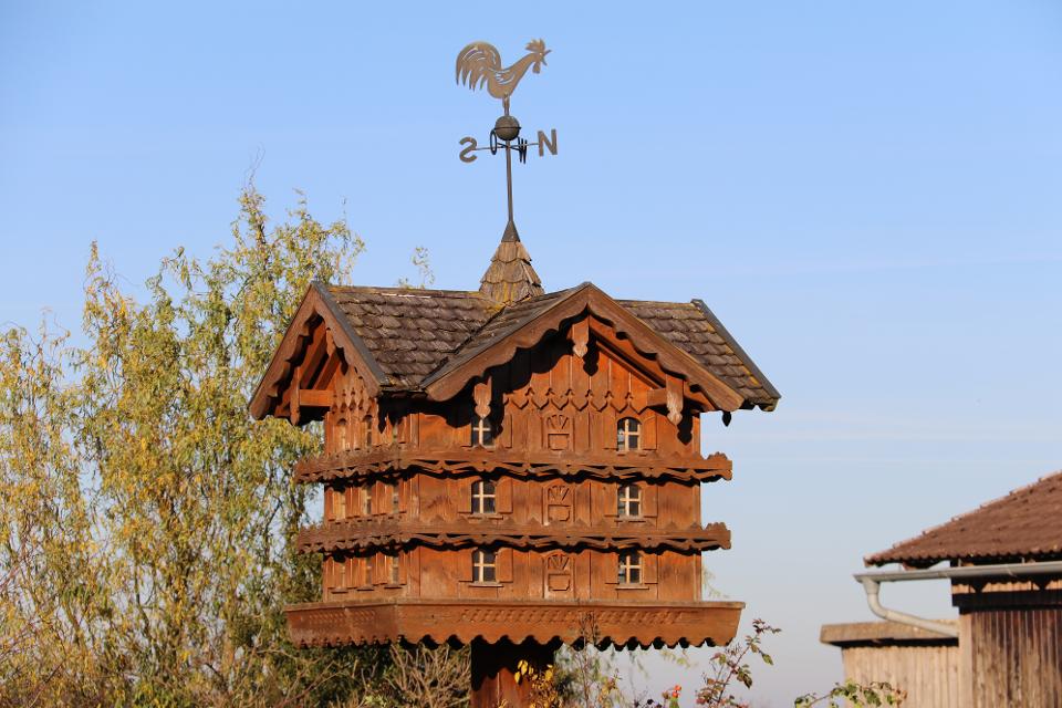 Taubenkobel gehören in Niederbayern zum Erscheinungsbild prächtiger Bauernhöfe. Egal ob versteckt auf dem Dachboden oder als prächtiges „Schloss“ weithin sichtbar mitten am Hof, Taubenkobel sind kulturgeschichtliche Denkmäler. Denn einst war die Taubenzucht ein Privileg des Adels. Als es freigegeben wurde, wurden aus den Untertanen nicht nur fleißige „Tauberer“, also Taubenzüchter, vor allem die reichen Großbauern eiferten mit kunstvollen Taubenschlägen ihren einstigen Grundherren nach und demonstrierten so ihr neues Selbstbewusstsein.Bei einem Fotowettbewerb um den schönsten Taubenkobel im Landkreis, ausgelobt von Landrat Heinrich Trapp, wurde deutlich, wie viele dieser hölzernen Zeitzeugen es im Ferienland Dingolfing-Landau noch gibt.