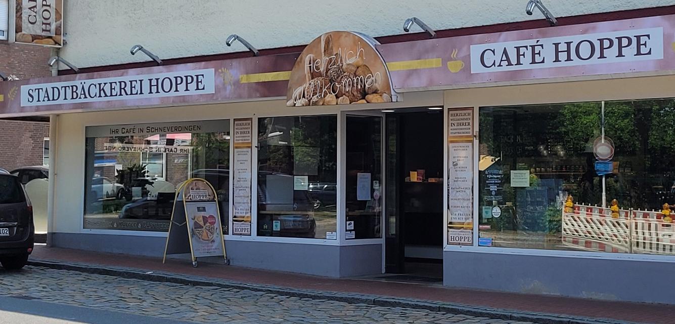 Stadtbäckerei Hoppe, Cafè Hoppe steht in dunklen Buchstaben auf einem Schild über dem Ladengeschäft mit großer Fensterfront.