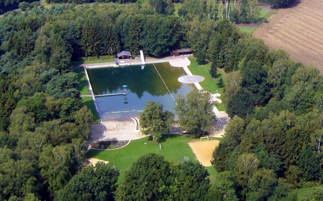 Das idyllisch gelegene Quellenbad bietet als Naturbad eine Wasserfläche von ca. 7.000 qm.
                 title=