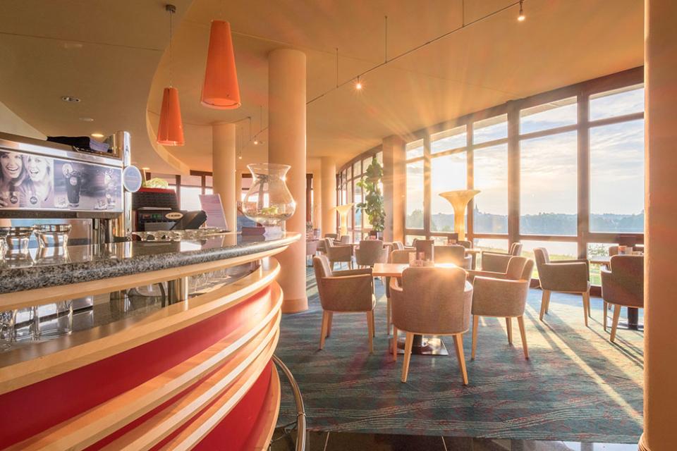 Die gemütlich eingerichtete Café-Lounge mit Bar in der Lobby des Kurzentrums steht nicht nur Hotelgästen, sondern auch allen anderen Besuchern von nah und fern offen.
                 title=