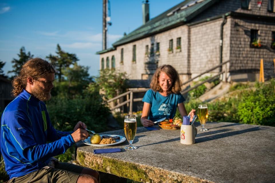 zwei Wanderer sitzen auf der Terrasse vom Kösseinehaus und essen