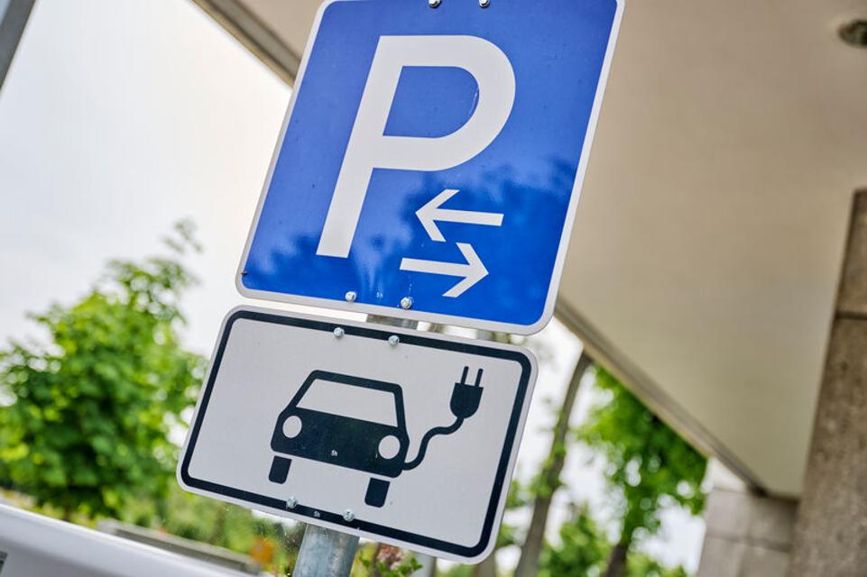 blaues Parkplatz-Schild mit einem Hinweis auf eine E-Auto-Ladestation