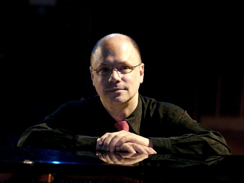 Profilfoto des Pianisten Thomas Hell vor schwarzem Hintergrund
