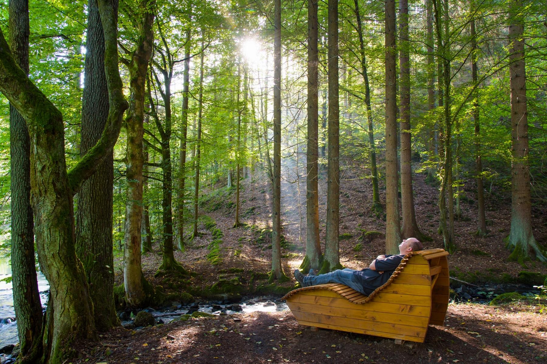 Mann liegt auf einer Entspannungsliege im Wald.