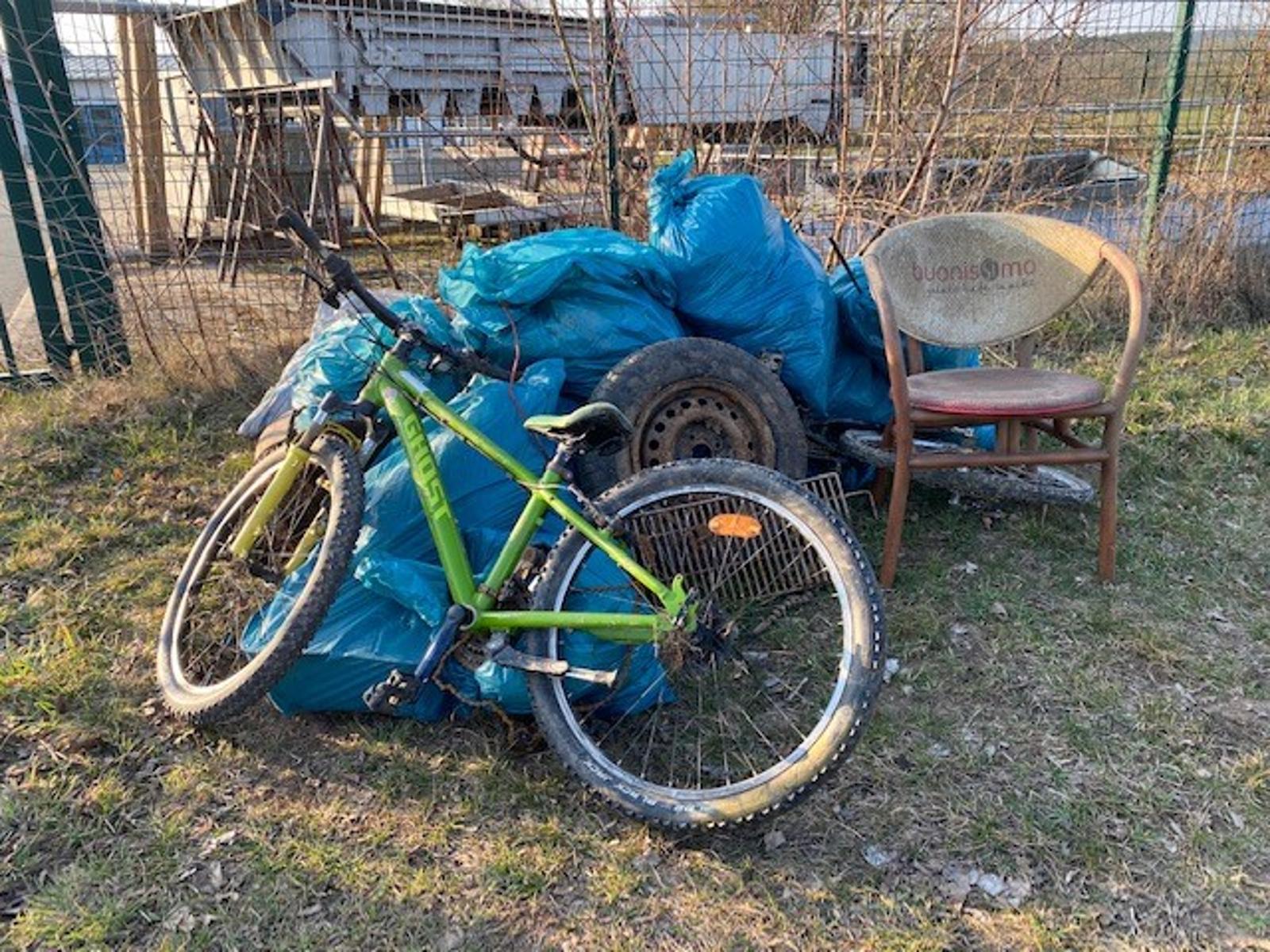 Müllberg mit Fahrrad, gefüllten blauen Müllsäcken und Stuhl