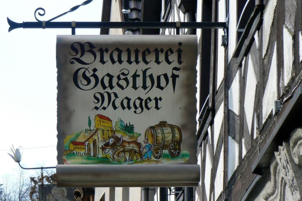 Schild der Brauerei Mager an der Hausfassade des Brauereigasthofs.
                 title=
