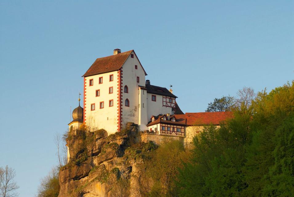 Die Burg thront auf einer Felsnadel und wird von der Abendsonne angestrahlt.