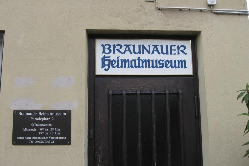 Dunkle, hölzerne Eingangstür mit der Aufschrift Braunauer Heimatmuseum.
                 title=