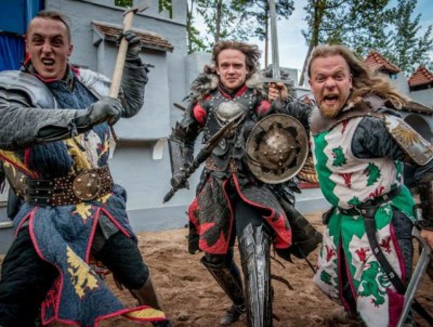 Drei Personen, als Ritter verkleidet. Teil einer Rittershow. Sie tragen Schwerter und Schilder, der Blick ist angriffslustig.