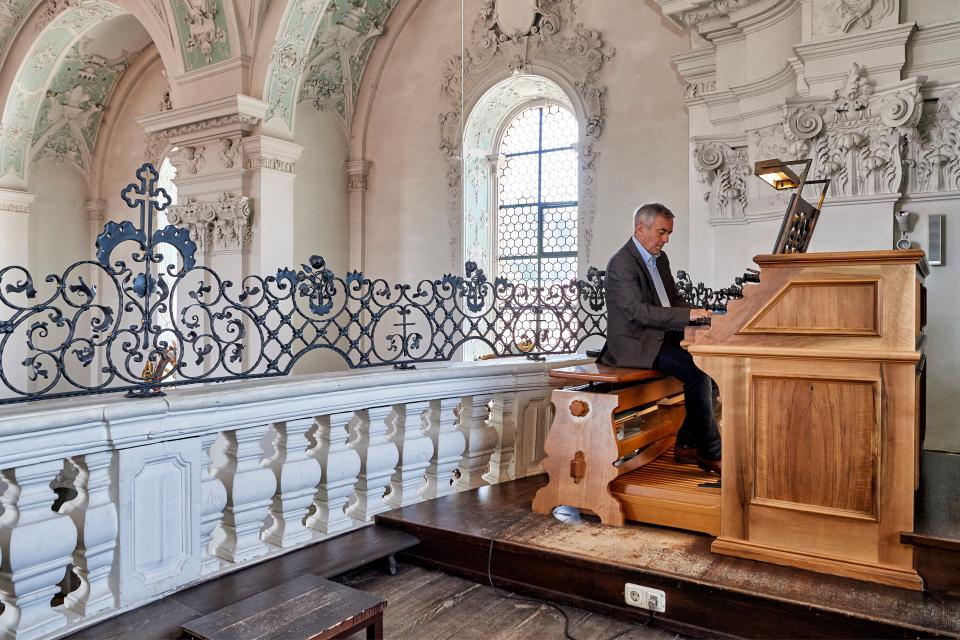 Ein Mann sitzt in der Kirche an der Orgel und spielt ein Musikstück.