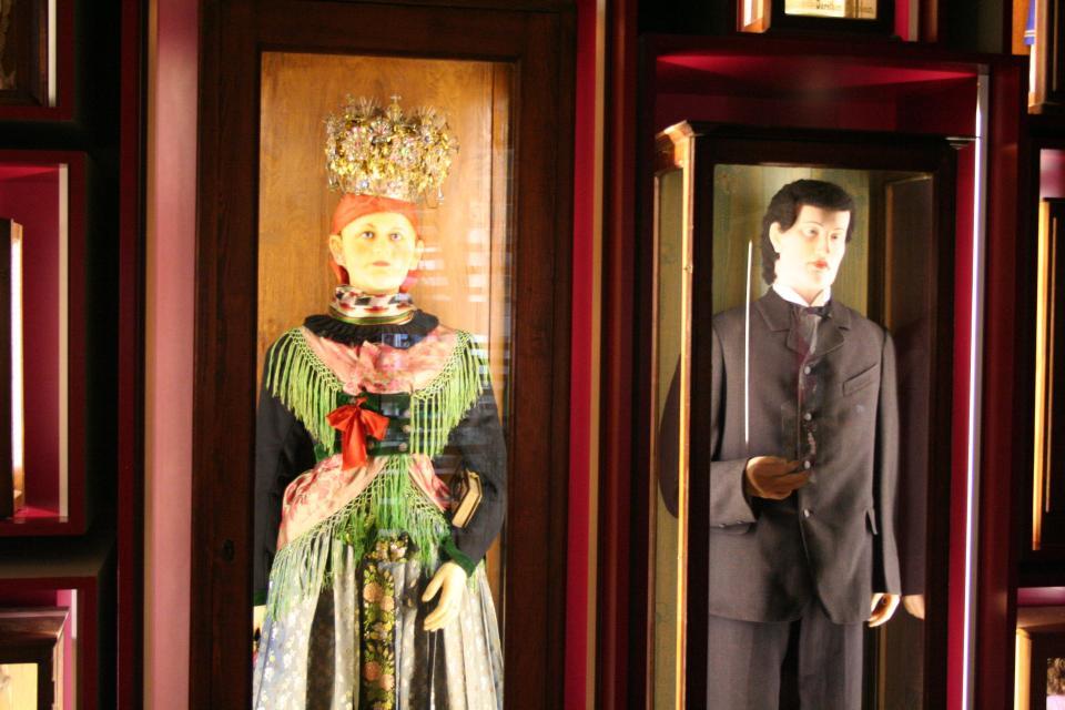 Detailaufnahme von zwei Wachsfiguren (ein Mann und eine Frau) in Tracht. Die Figuren stehen in Glasvitrinen die beleuchtet sind.