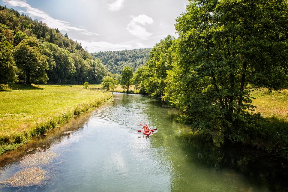 Auf einem ruhigen Fluss in herrlicher Natur gleitet ein Kanu dahin.