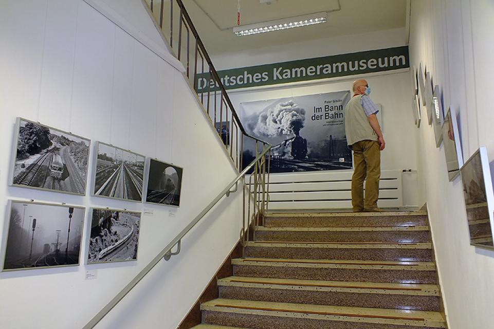 Ein Mann steht im Treppenhaus und blickt auf die ausgestellten Fotografien.