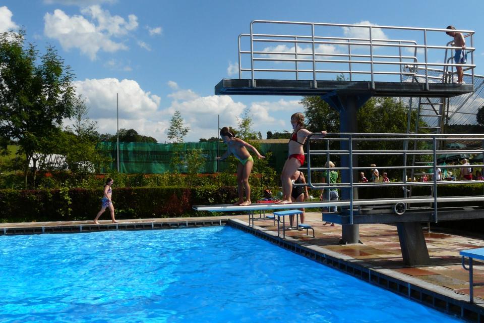 Jugendliche springen vom Sprungturm ins Becken