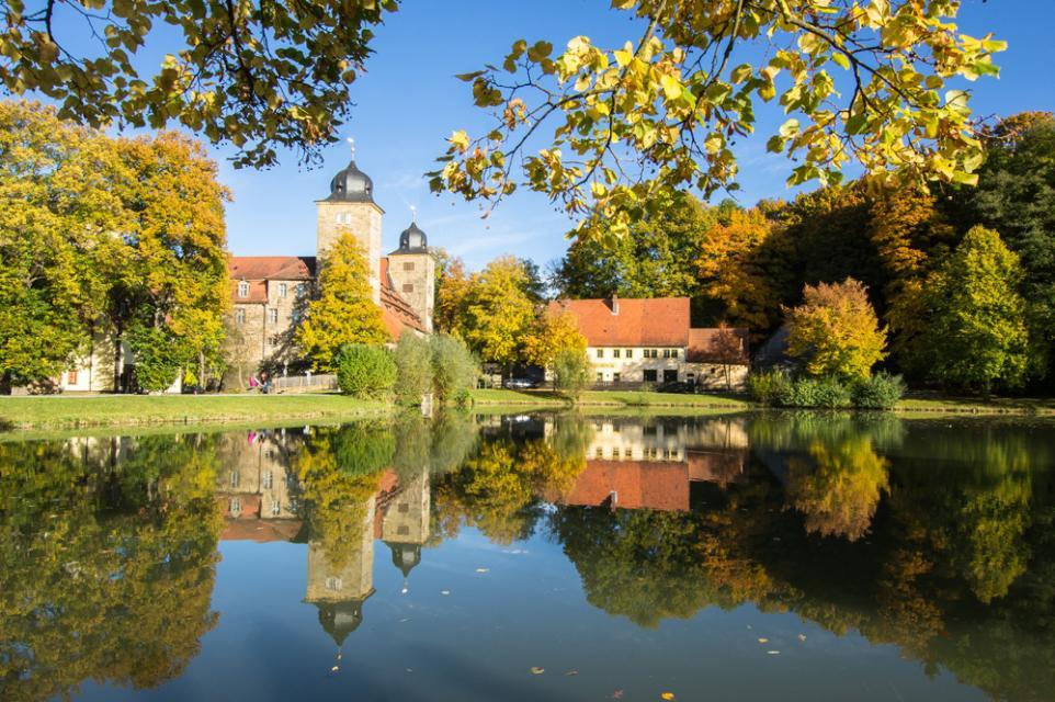 Im See, welche im Schlossgelände integriert ist, spiegeln sich das Schloss und die Brauereigaststätte "Schlossbräu". Es ist ein herbstliches Bild, die Blätter sind bereits in orange-braun Tönen gefärbt.