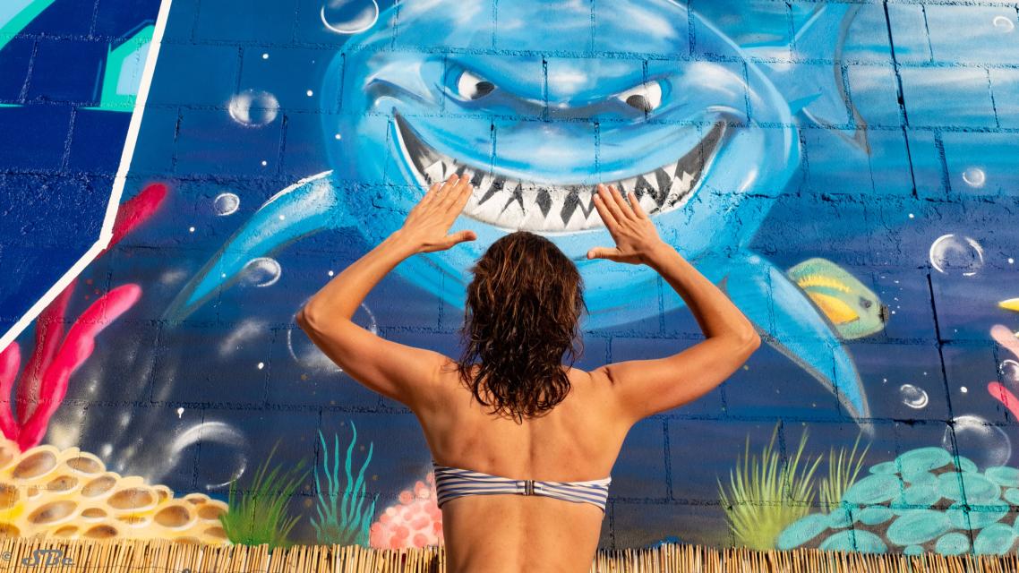eine junge Frau betrachtet ein Wandbild mit Figuren aus "Findet Nemo"
