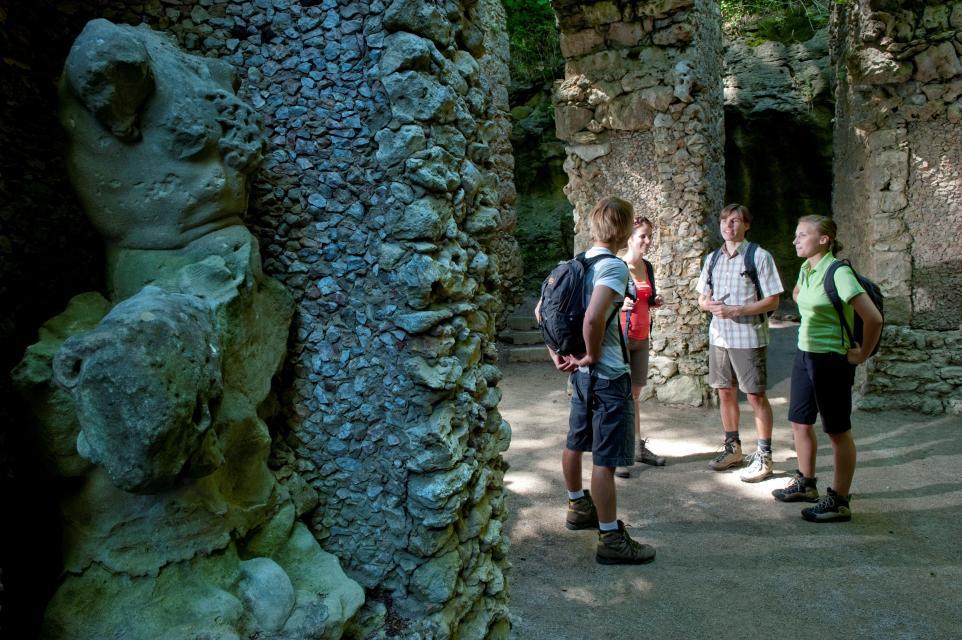 Vier Wandersleut unterhalten sich inmitten des Gebildes. Gut zu erkennen sind verschiedenste Steinformen, welche für dieses kunstvolle Barockwerk verwendet wurden.