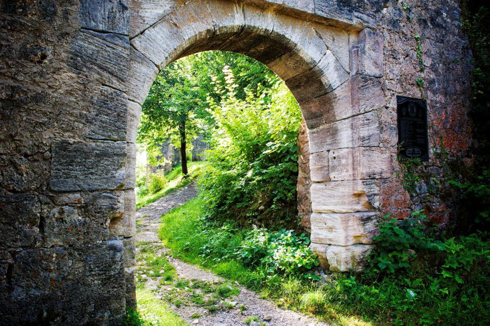 Ein Weg führt durch ein altes, steinernes Tor berauf.