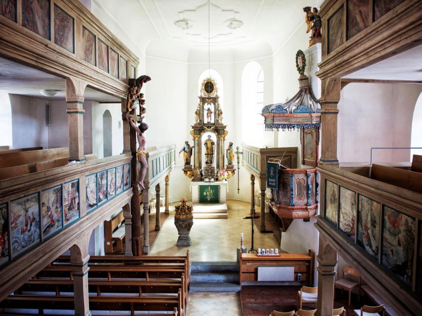 In der Muggendorfer St. Laurentiuskirche befinden sich zweistöckige Emporen aus Holz, welche mit vielen Gottesbildern verziert sind. Die Kanzel befindet sich mittig im Gebäude zwischen Sitzbänken und Altarraum.
                 title=