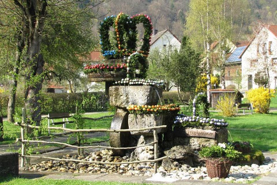 Osterbrunnen mit markanten Mahlsteinen im Kurpark von Behringersmühle
