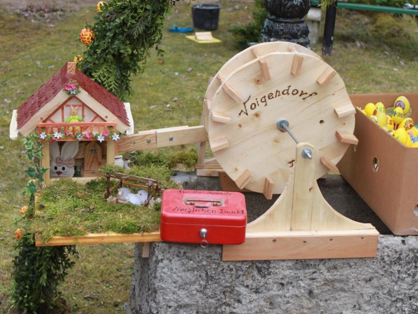 Miniaturansicht einer Mühle mit Fachwerk, zu der Ein Wasserrad aus Holz führt, welches man an einer Kurbel drehen kann.