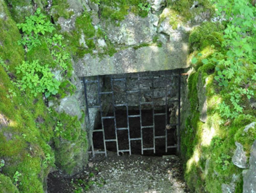 Ein vergitterter, von Fels umfasster Eingang zum Brunnenloch.