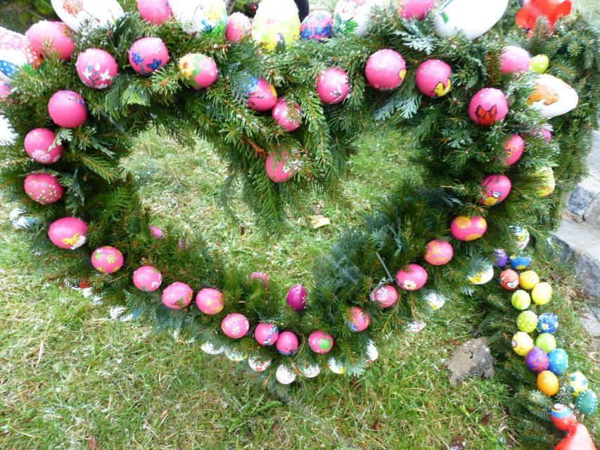 Ein aus grünen Nadelzweigen und rosa Eiern geformte Herz.