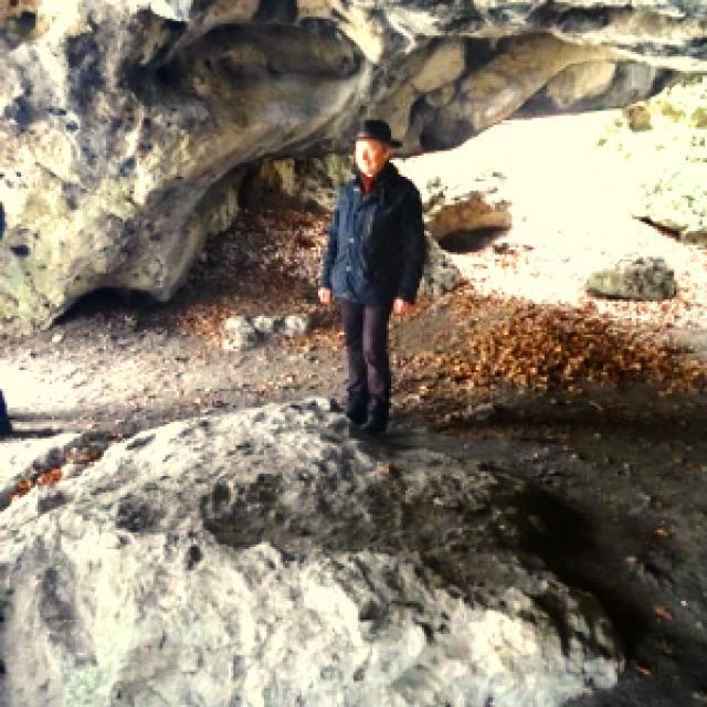 Ein Mann steht in einem natürlich Felsbogen und bewundert die Höhle.
                 title=