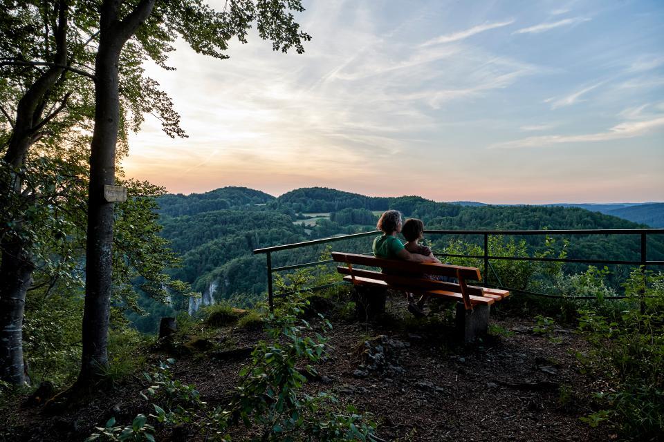 Ein Paar sitzt auf einer Bank am Geländer des Aussichtspunktes und blickt in die Ferne