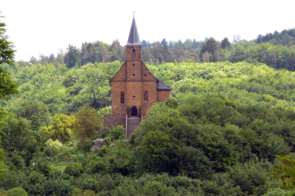 Die Wallfahrtskirche steht imposant auf einem Felsen und erhebt sich aus den umliegenden Wäldern.
                 title=