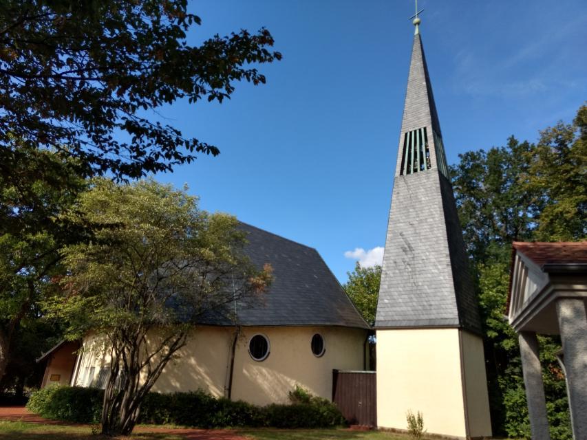 Der Glockenturm, welcher mit einem hohen, spitzen Dach empor steht, ist mit schiefernen Platten bedeckt. Das Kirchengebäude in naher Umgebung ebenfalls.
