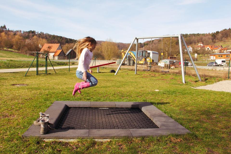Ein junges Mädchen springt auf einem in den Boden eingelassenen Trampolin