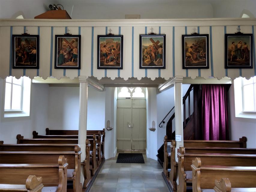 An der weiß-blau gestreiften Empore hängen sechs Gemälde, welchen den Kreuzweg von Jesus zeigen.