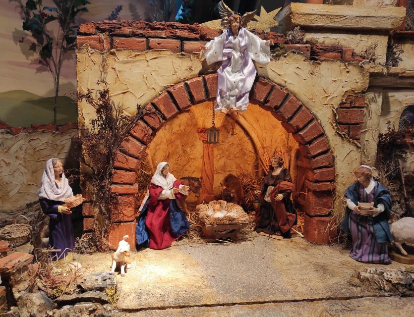 Orientalische Krippe, über der ein weißer Engel schwebt. In der Krippe stehen Maria und Josef vor dem Trog mit dem Jesuskind.