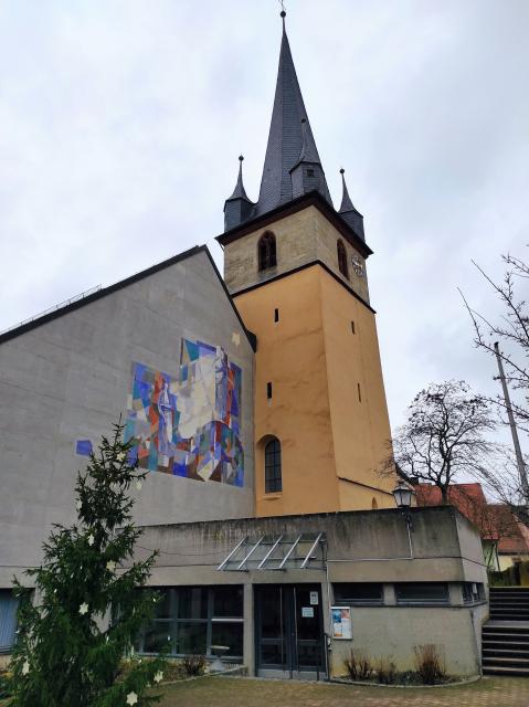 Die moderne Kirche mit Zeltdach wurde 1972 geweiht. Der Turm der alten Barockkirche von 1719 ist erhalten.
                 title=