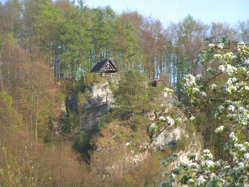 In bewaldeter Umgebung thront auf einem Felsbrocken ein hölzerner Aussichtspavillon.