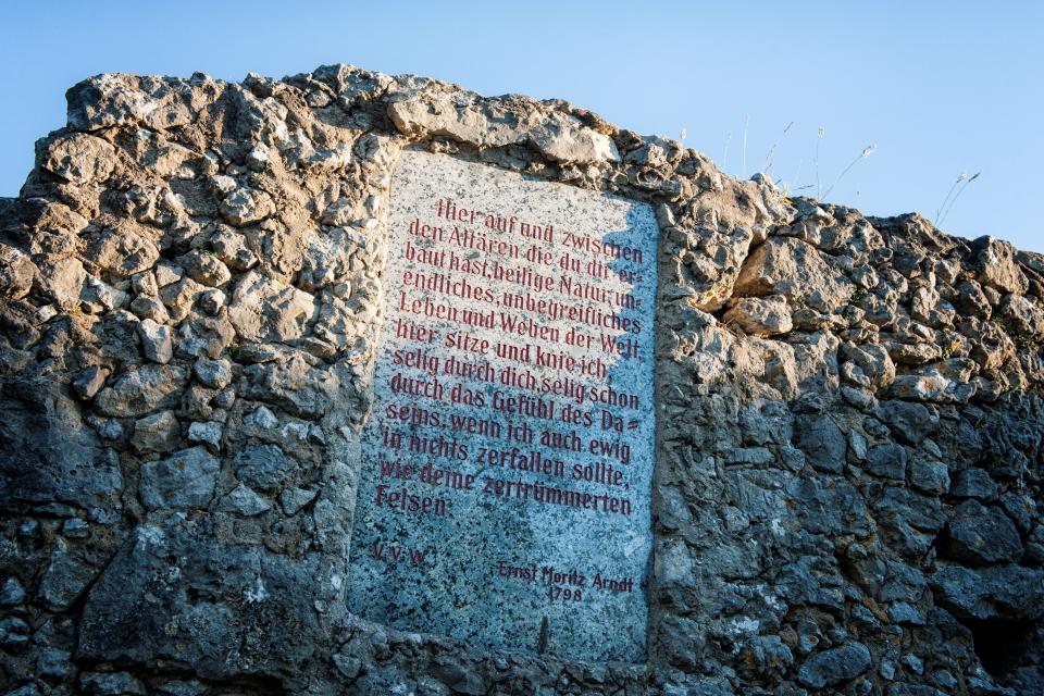 In einer Mauer aus Natursteinen ist eine graue Gedenktafel eingebunden. Der Inhalt ist nicht lesbar.