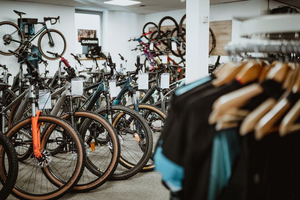 Aneinandergereihte Fahrräder und Fahrradkleidung in einem Verkaufsraum.
