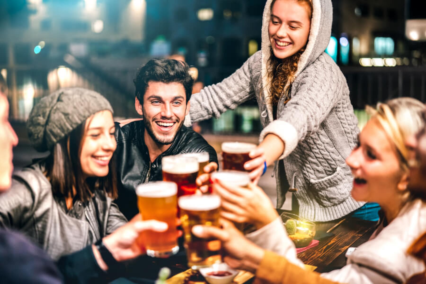 Junge Leute stoßen mit Bier an und sind fröhlich