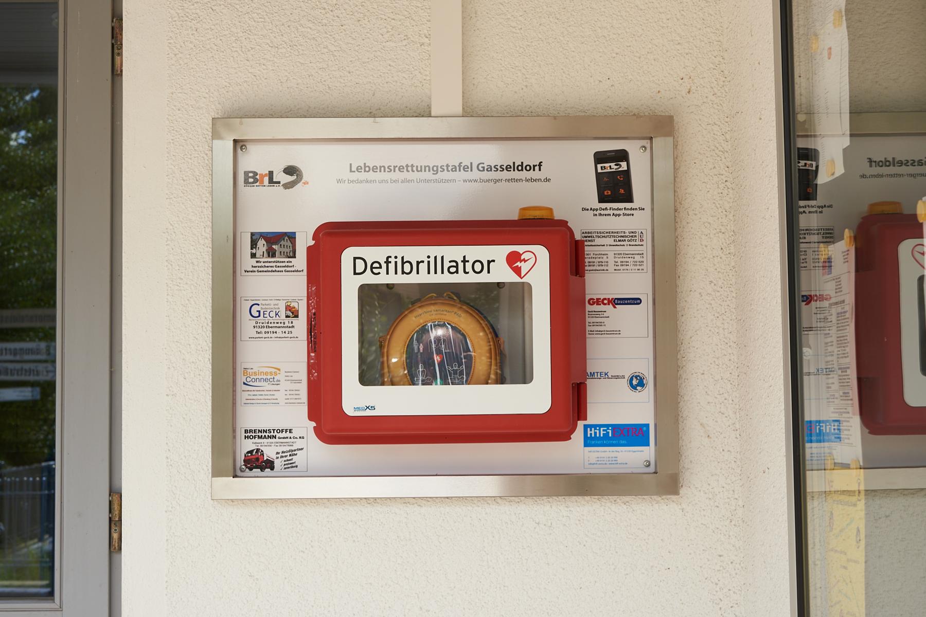 Defibrillator direkt an der Außenwand, rechts neben dem Eingang, Nahaufnahme