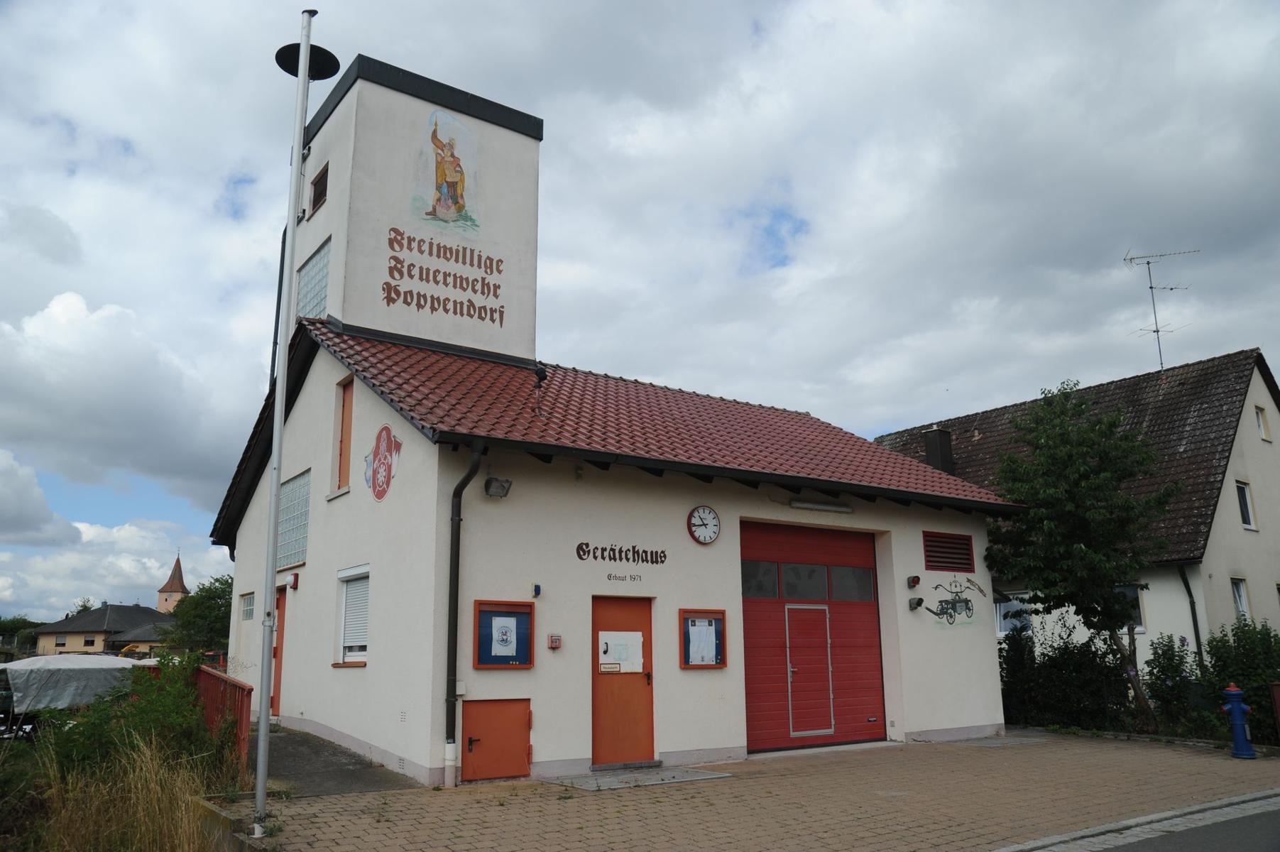 Defibrillator am Feuerwehrhaus Poppendorf, in der Tür mit dem Hebel (Not gesichert), links vom Fahrzeugstor