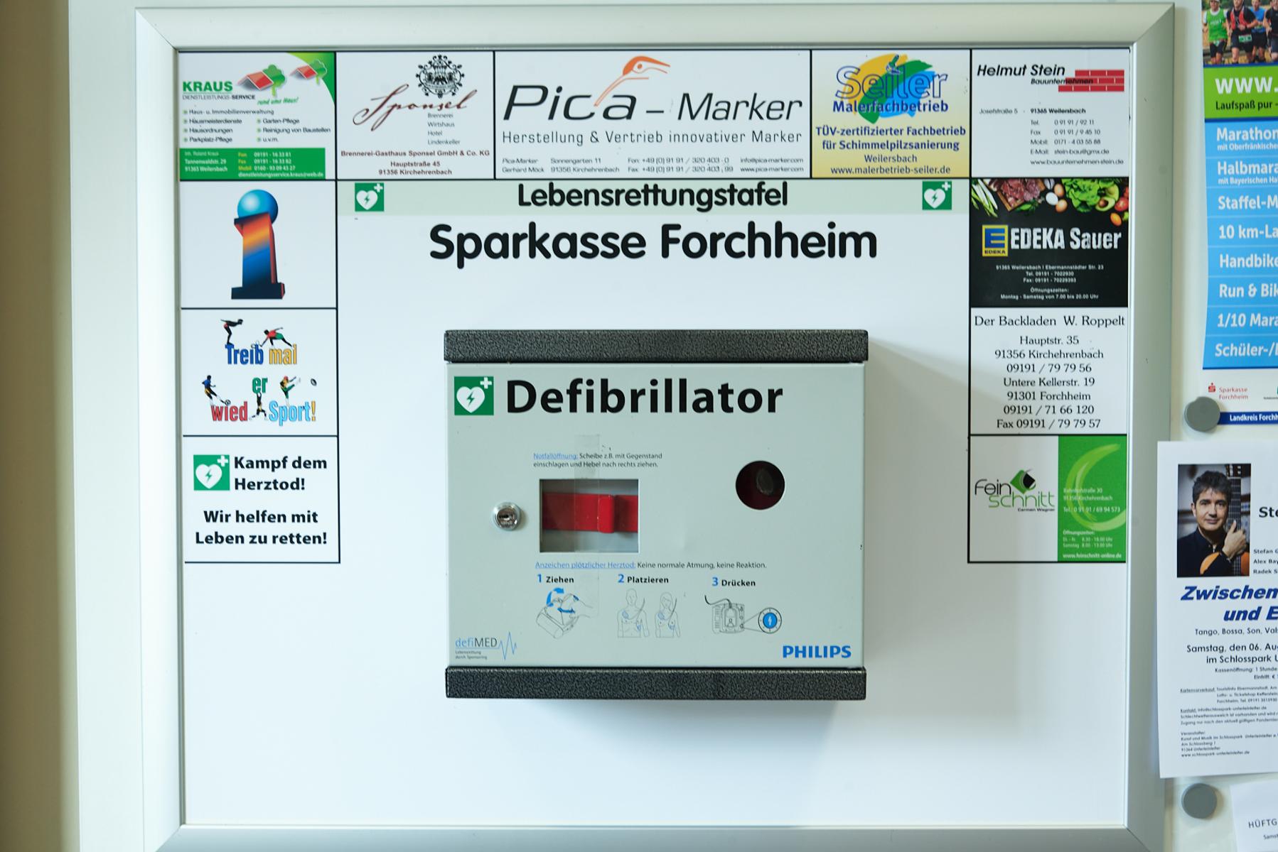 Defibrillator Sparkasse Kirchehrenbach, Nahaufnahme, Wand links im Vorraum