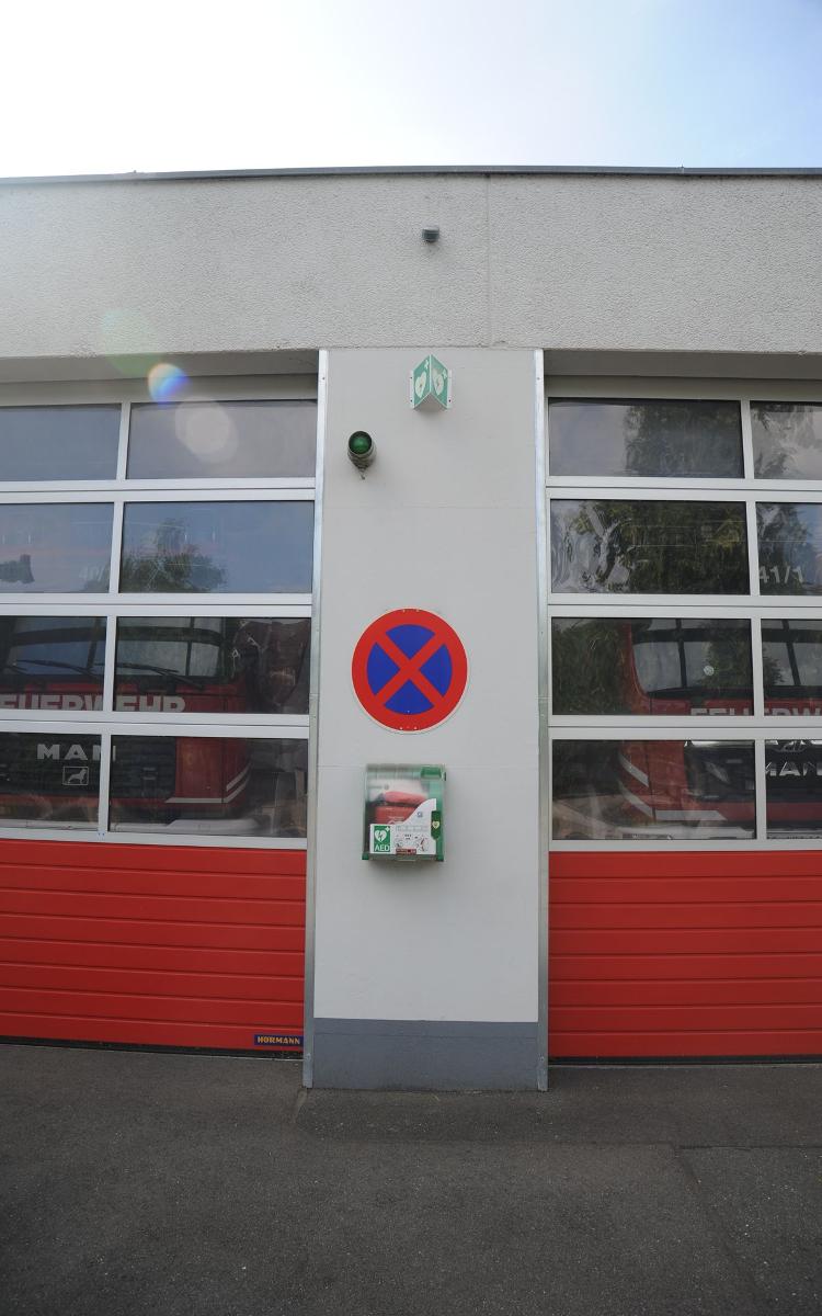 Defibrillator Neunkirchen am Brand Freiwillige Feuerwehr, Nahaufnahme, unter Halteverbotsschild, Außenwand Fahrzeughalle (Front) zwischen Tor 2 und Tor 3