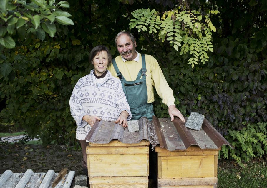 Eine Frau und ein Mann stehen vor den Bienenkästen