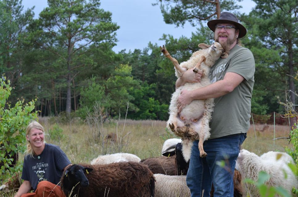 Ein Mann hat ein Schaf auf seinem Arm.