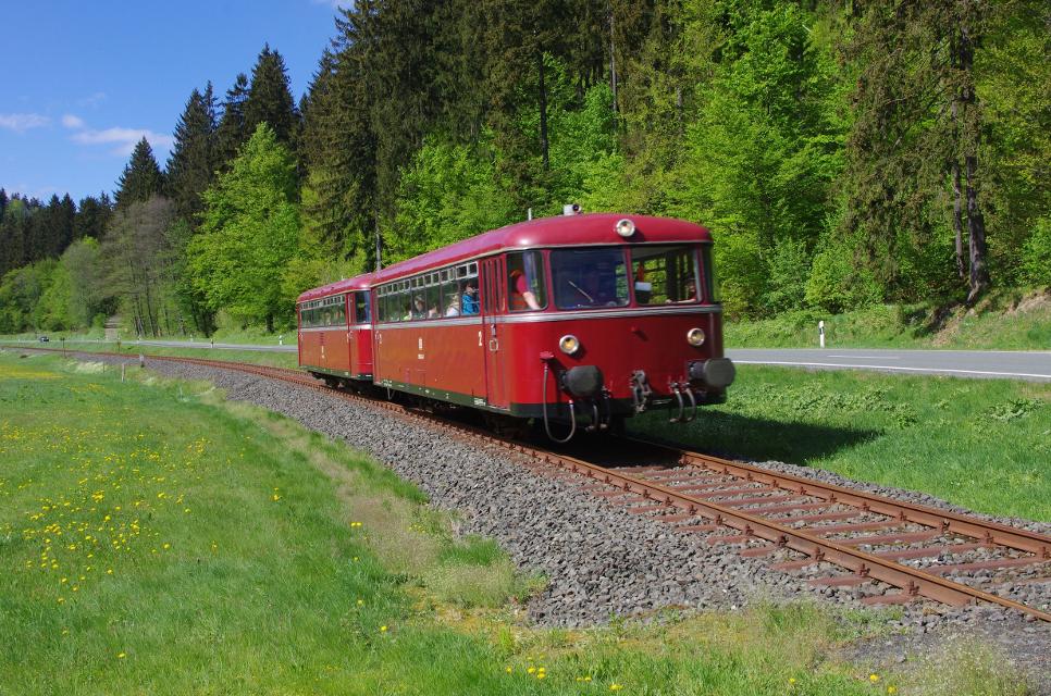 Ein historischer, roter Zug fährt durch die Landschaft.